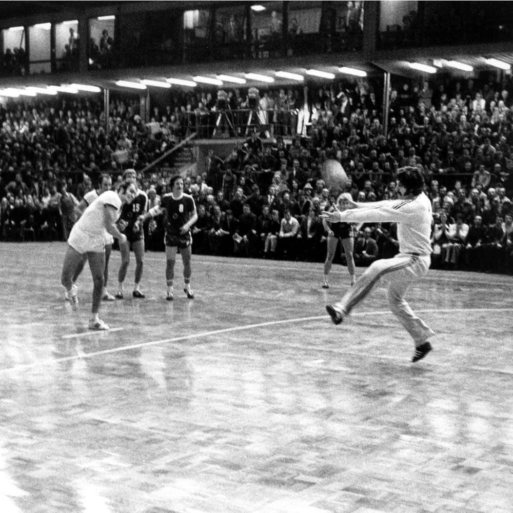 DDR-Spieler Hans Engel (M, vorn) wirft, aber BRD-Torhüter Manfred Hofmann (r) pariert in der Schlußsekunde den entscheidenden Siebenmeterball. Die DDR-Handballnationalmannschaft gewinnt am 06.03.1976 in Karl-Marx-Stadt zwar das entscheidende Olympia-Qualifikationsspiel gegen die Bundesrepublik mit 11:8, aber die Höhe des Sieges reicht nach dem verlorenen Hinspiel nicht. Das bundesrepublikanische Team qualifiziert sich in diesem Handball-Krimi für die Teilnahme an den Olympischen Spielen in Montreal, wo die Mannschaft Vierter wird.