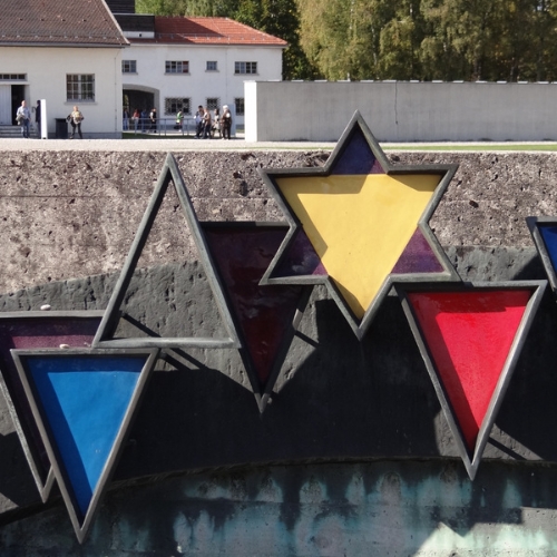 Kunstwerk in der KZ-Gedenkstätte Dachau. Blaues, rotes und graues Dreieck, gelber Stern. Es fehlen "schwarze" und "grüne" Winkel.