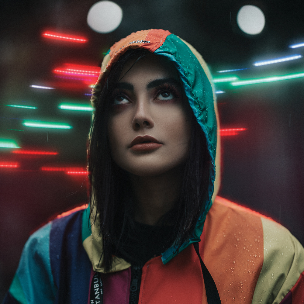 Foto einer jungen Frau mit bunter Jacke und Kapuze