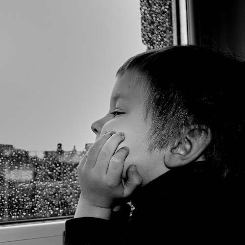 Trauriges Kind sitzt am Fenster