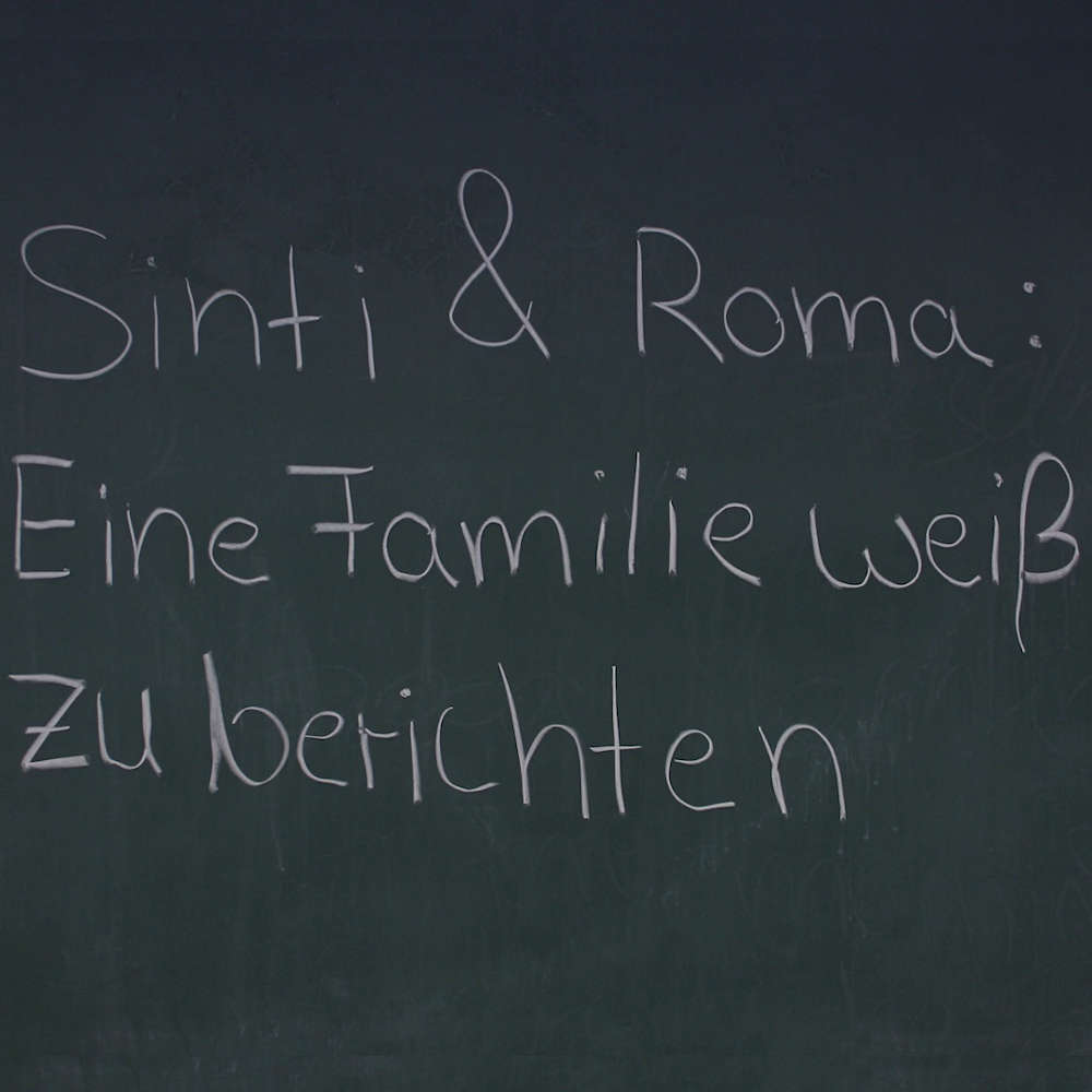 Schriftzug "Sinti & Roma: Eine Familie weiß zu berichten" mit Kreide auf einer Tafel